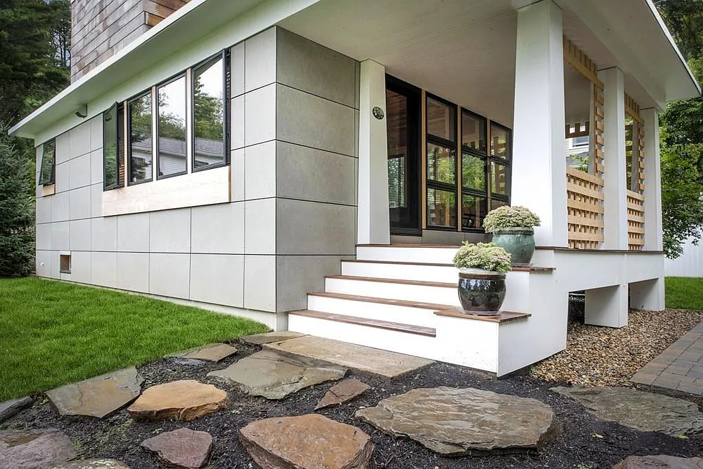 Exterior view of a modern residential home with fiber cement paneling and natural stone pavers